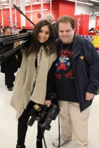 A man and woman posing for the camera in front of cameras.