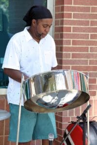 A man playing the steel drum outside of a building.