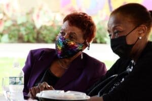 Two women wearing masks are sitting at a table.