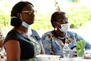 Two women wearing masks and glasses are sitting at a table.