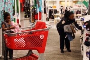 A person in black jacket near red shopping cart.