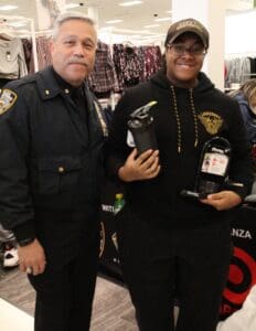 Two men in police uniforms holding a bottle of alcohol.