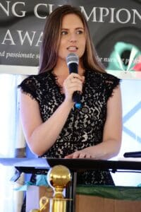 A woman in black dress holding a microphone.