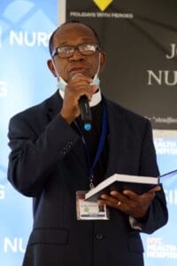 A man holding a book and speaking into a microphone.