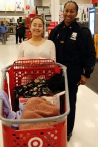 A woman pushing a shopping cart with clothes in it.