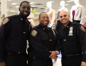 Three police officers posing for a picture in front of mannequins.