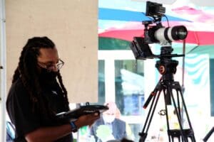 A man holding a tablet in front of a camera.