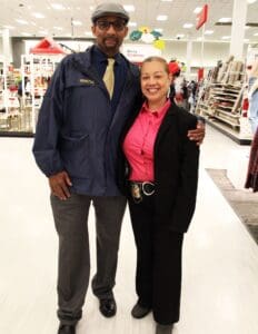 A man and woman posing for the camera in front of a store.