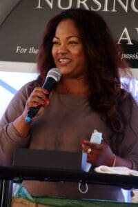 A woman is speaking at an event with microphone.