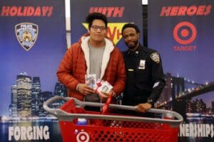 A man and a police officer standing next to a red shopping cart.