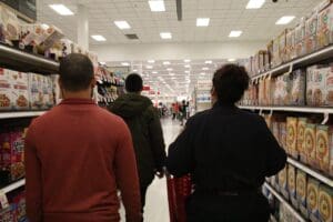 A group of people walking through a store aisle.