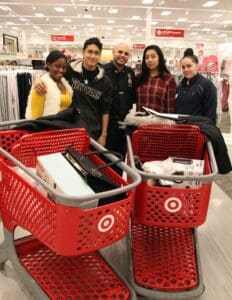 A group of people standing around two red shopping carts.