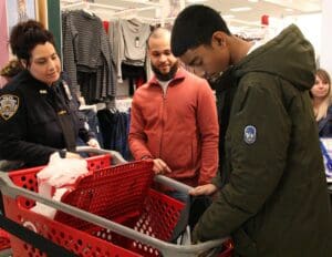 A man is pushing a shopping cart while two other men look on.