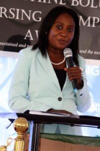 A woman is speaking at an event with a microphone.