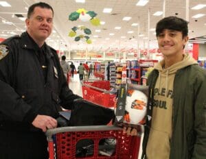 A man and a police officer in front of a shopping cart.