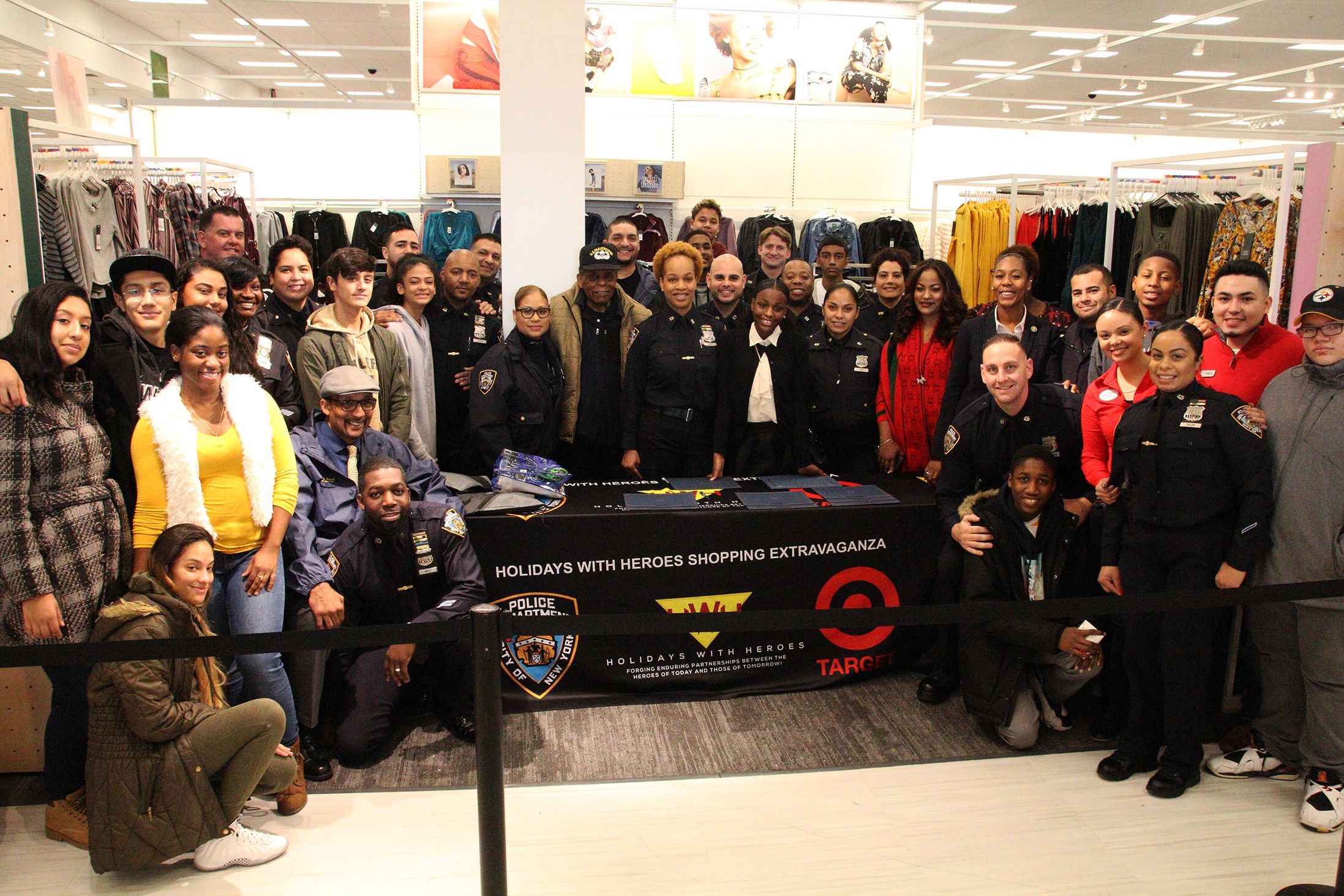 A group of people posing for a picture in front of a batman costume.